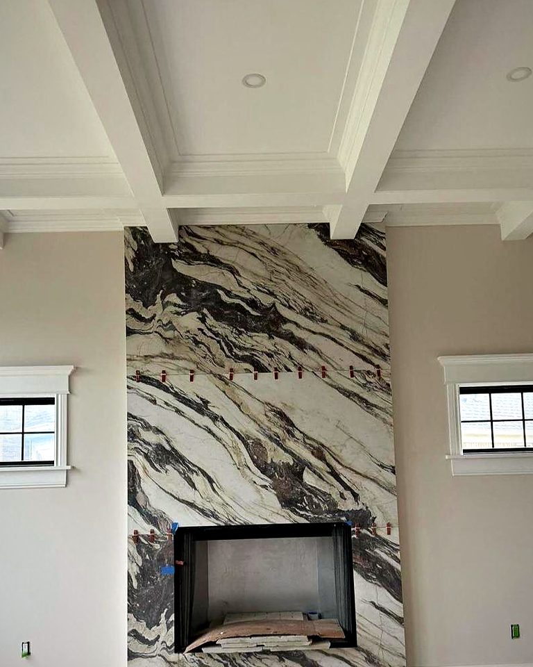 Dramatic black-and-white veined slab fireplace surround under a coffered ceiling