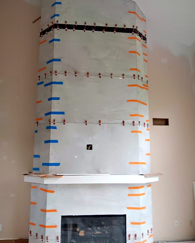 Angled fireplace column with large tiles taped and clipped while the setting bed cures