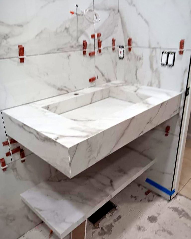 Floating mitred vanity and shelf wrapped in marble-look porcelain, mid-installation